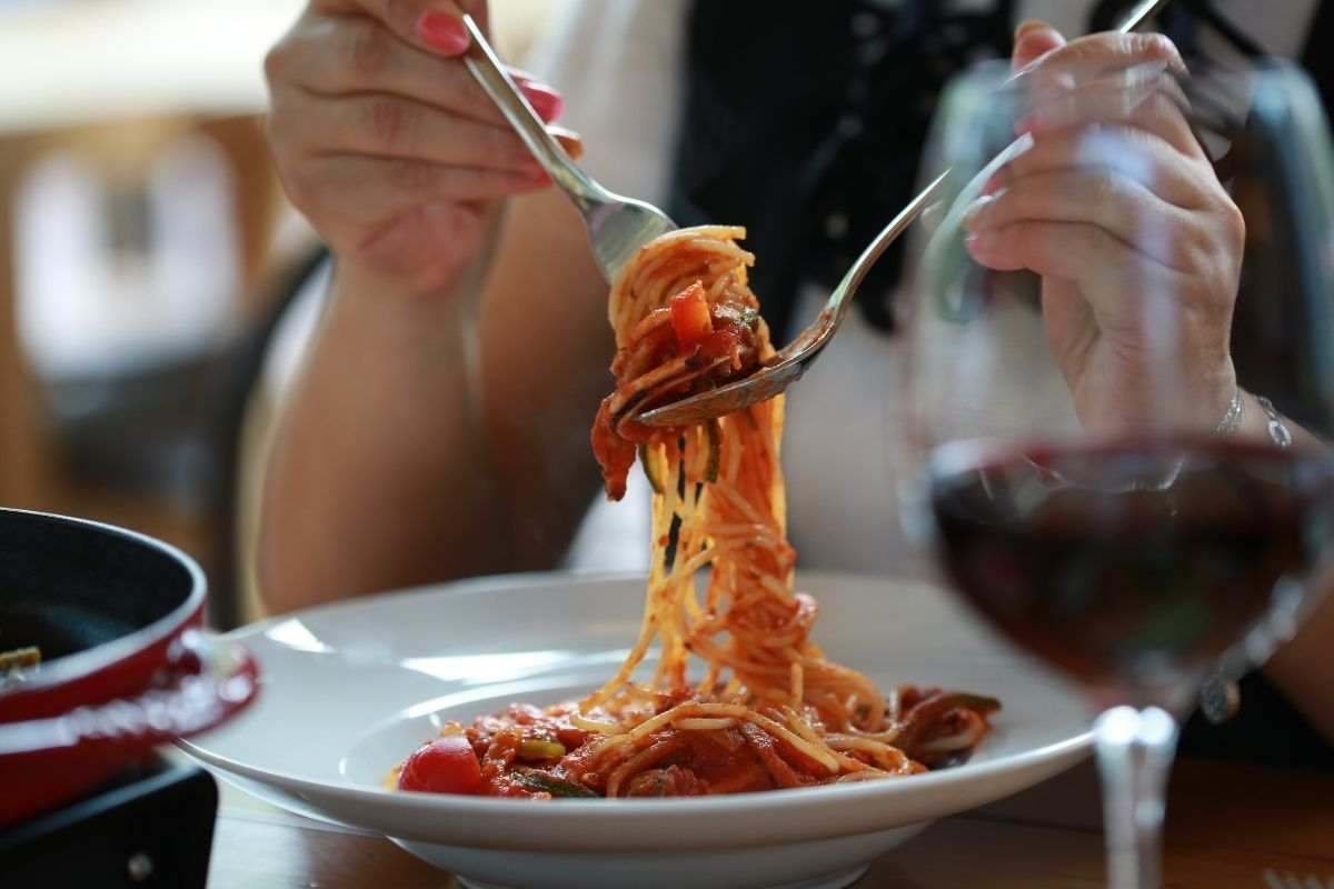 Piatto di pasta accompagnato da una bicchiere di vino