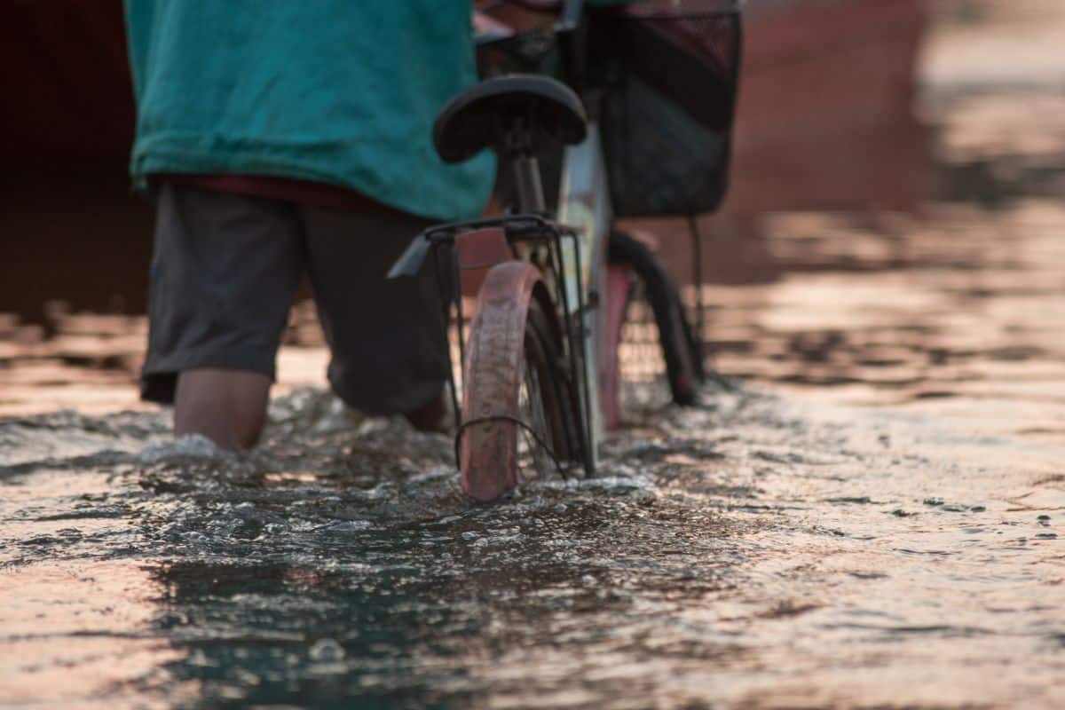 Uomo con bicicletta durante un alluvione